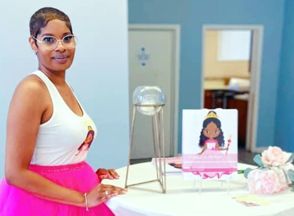 Carmen Hayes, wearing a pink tutu and white tank top, posing next to her Princess Nellie character illustration. 