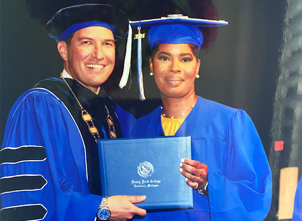 President Russ Kavalhuna wearing regalia with Carmen Hayes to his right holding her diploma.