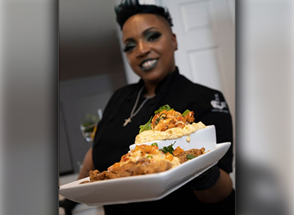 Tiffany Williams is holding her dish of Cajun-fried catfish with white cheddar gouda cheese grits topped off with lobster-lemon butter sauce and garlic shrimp. 