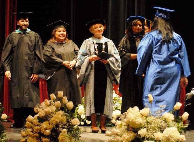 Dr. Mee (center) awards an HFCC student her degree.