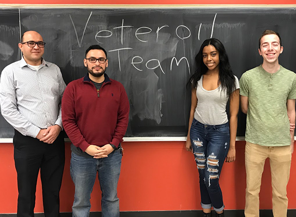 Breanna Allen in front of a chalkboard, with three men from the Engineering Club