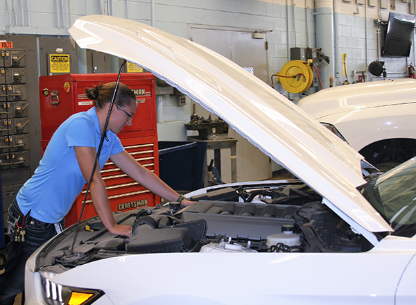 Ashley Smith, HFC's first female automotive faculty member, checks under the hood of a car. 