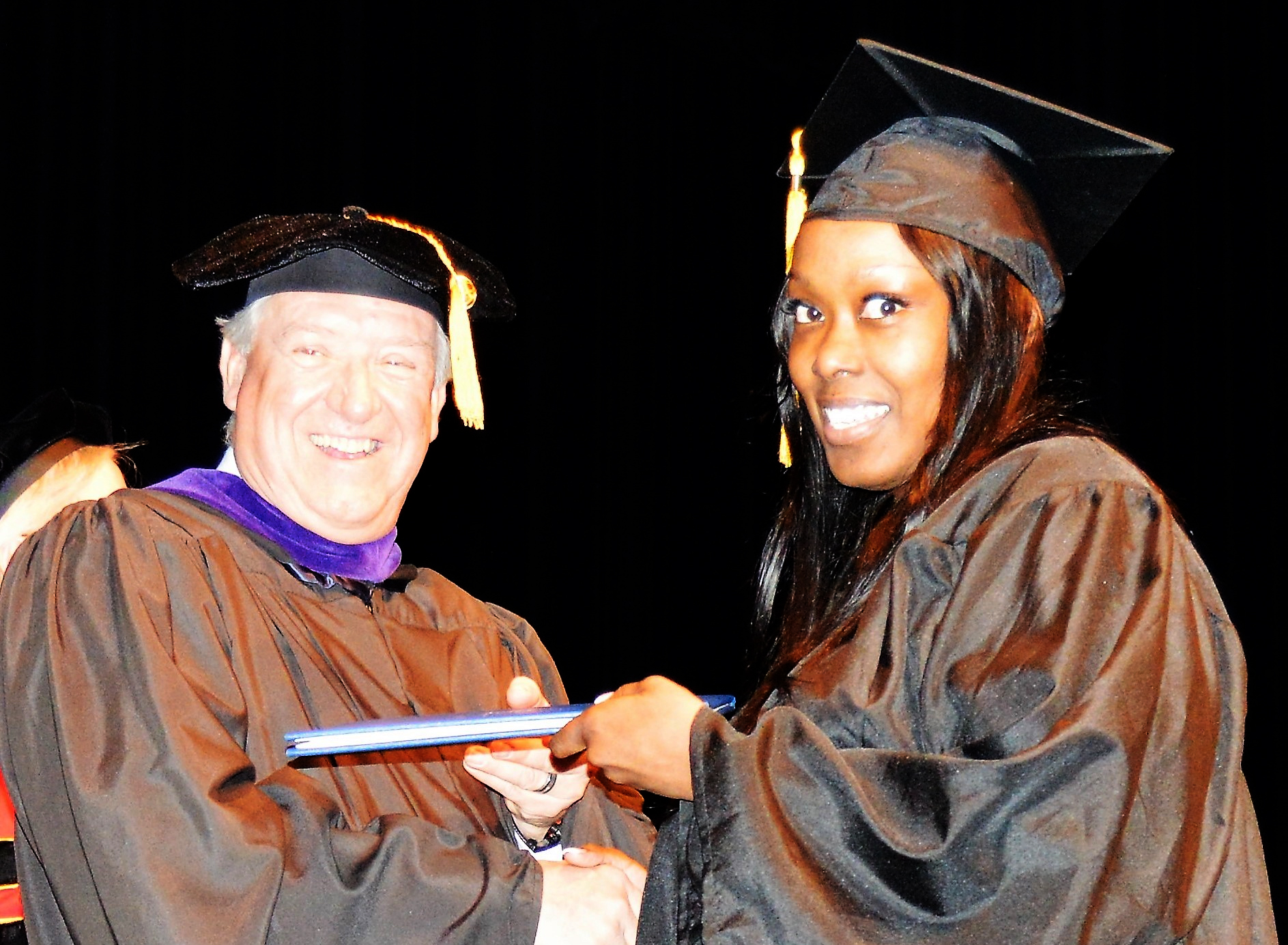 Interim President John Satkowski gives a graduate her diploma