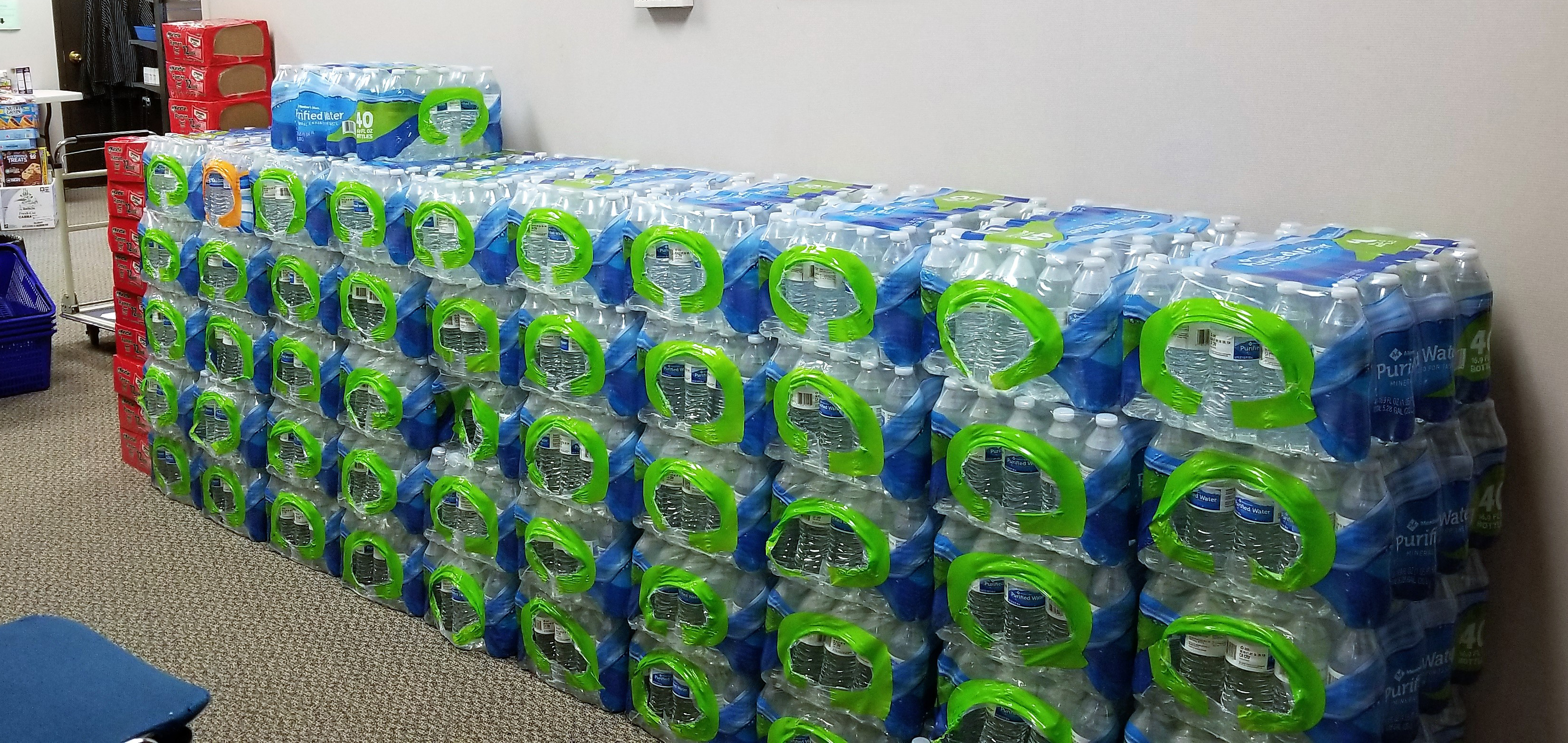 dozens of cases of bottled water stacked against a wall