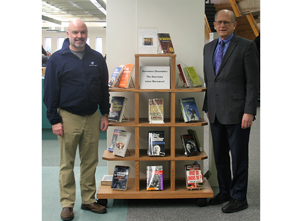 Eric Rader and John McDonald stand next to a book display