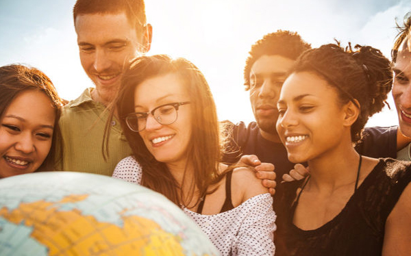 Diverse students facing a globe, smiling