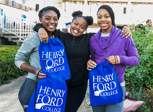 Three students holding HFC backpacks