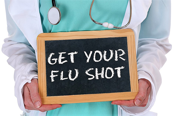 health care worker holding a sign with "Get Your Flu Shot"