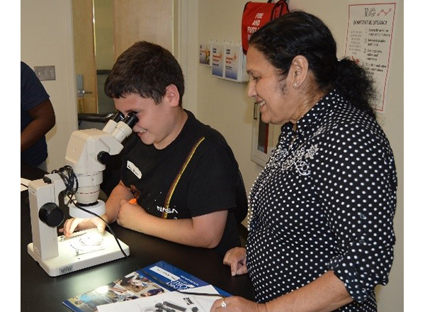 HFC biology instructor Mary Parekunnel shows a student how to use a dissecting microscope. 