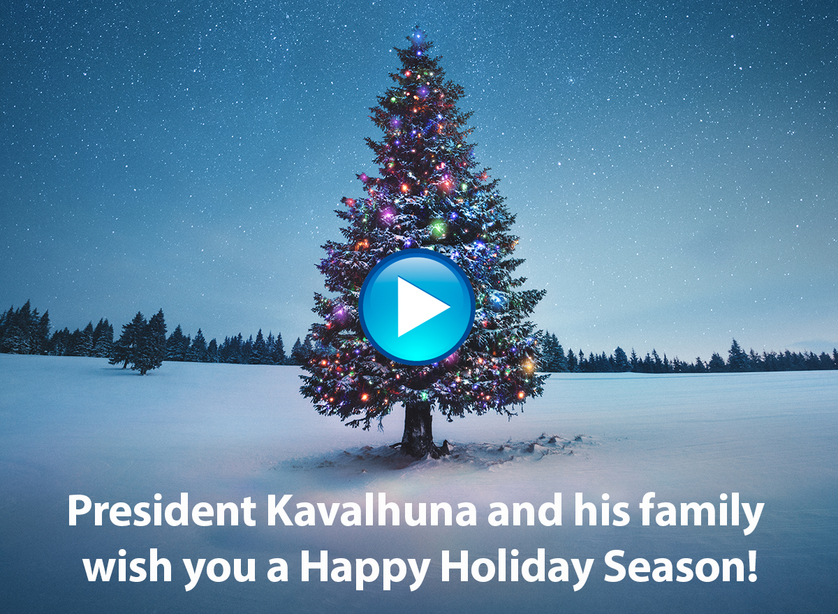 Photo of a tree in the snow, decorated, and the words "President Kavalhuna and his family wish you a happy holiday season!"