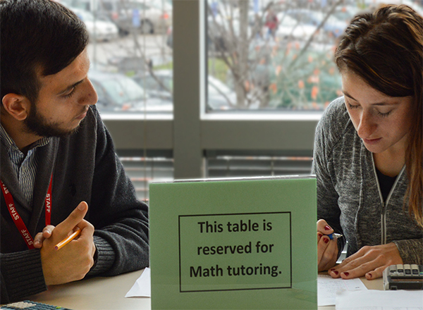 Tutor and student at a table with a sign that the table is reserved for tutoring