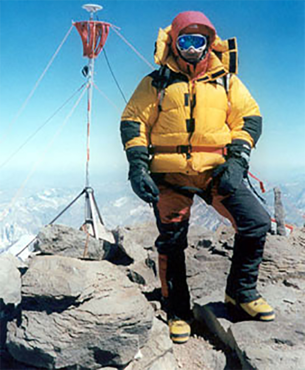 Man in mountain gear standing on summit.