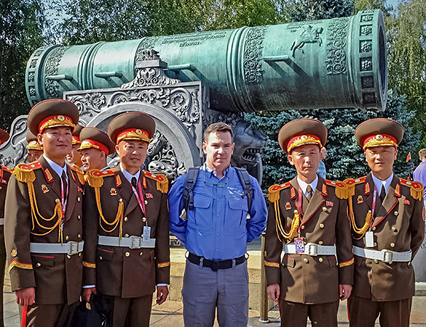 Four North Korean soldiers and one American civilian standing in front of a ceremonial cannon.
