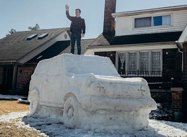 Man standing, waving, on top of snow sculpture