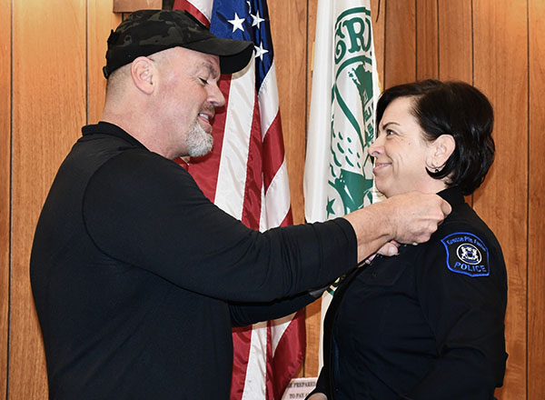 Lt. Jim Cashion of the Detroit Police Dept. proudly pins the badge on his wife, Veronica Cashion, a Grosse Pointe Farms public safety officer, as she was reinstated after major injuries sidelined her. 