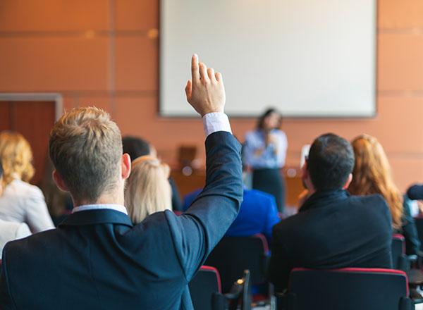 An image of a business person raising their hand during a presentation.