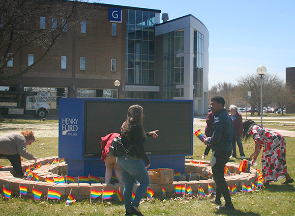 HFC students and employees work alongside each other, installing pride flags. 