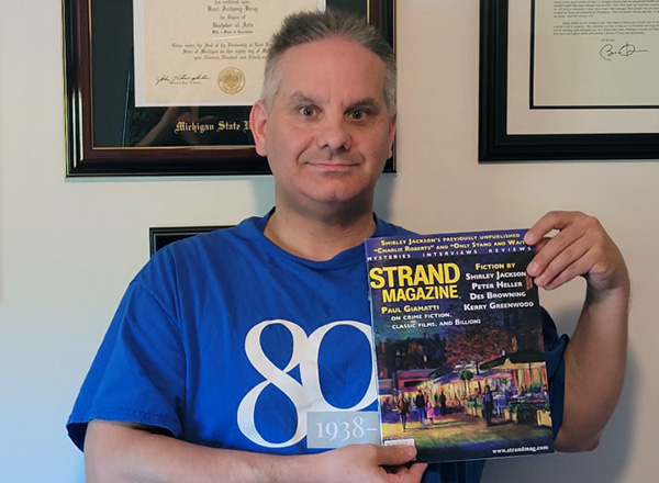 An image of Kurt Krug holding an issue of Strand Magazine. 