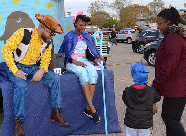 Volunteers dressed as "Toy Story" characters greet a Trunk or Treater. 
