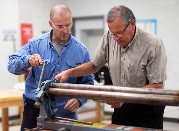 Two men working on metal fabrication.