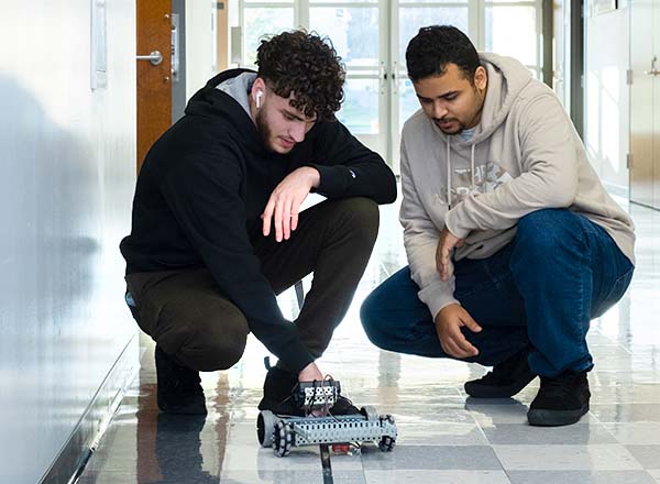 Pre-engineering students testing a small robotic vehicle.