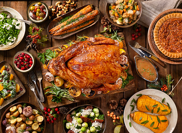 A turkey surrounded by several side dishes and a pecan pie. 