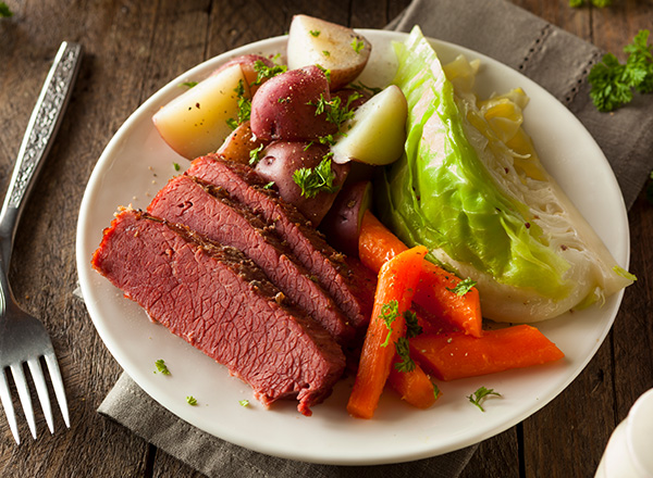 A plate of corned beef and cabbage with carrots and potatoes.
