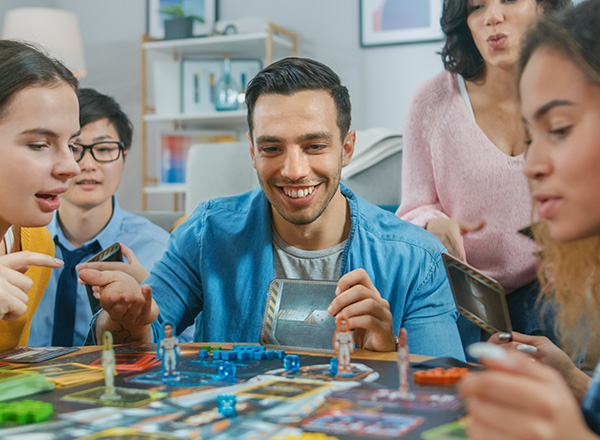Group of people playing in a board game with cards and dice. 