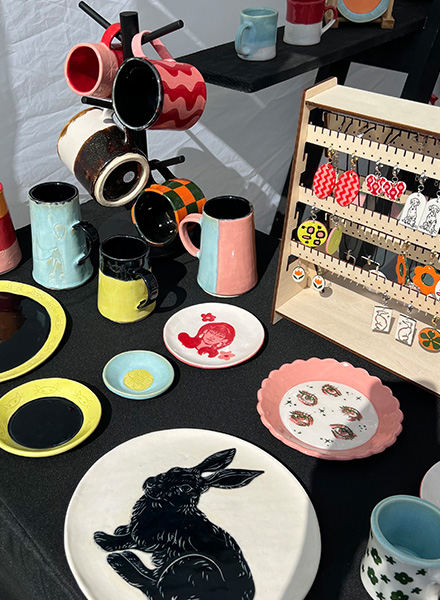 Assortment of ceramic plates, mugs, and jewelry created by Paige Deon.
