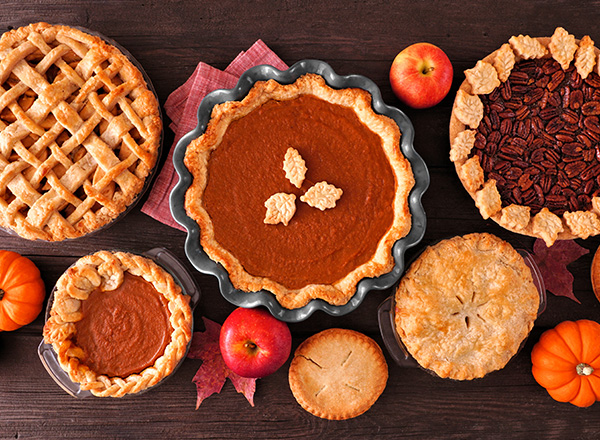 An above shot of fall baked goods like apple pie, pumpkin pie, and pecan pie.
