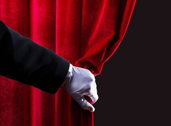 image of a hand pulling back a red curtain 