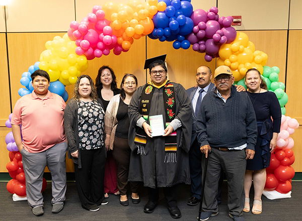 Jesus Cruz-Navarro with family under a rainbow of balloons.