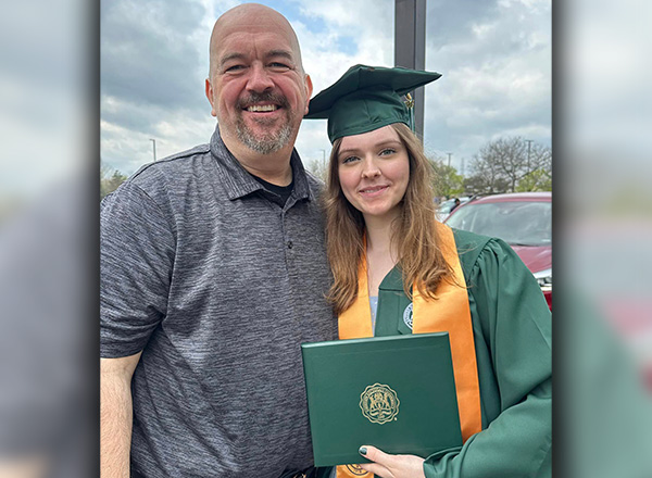   Alayna Kondraciuk, right, wearing Eastern Michigan cap and gown, holding her diploma standing next to her father, Jerry Kondraciuk, left.