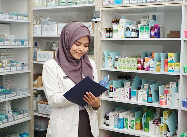 A woman wearing a hijab working in a pharmacy.
