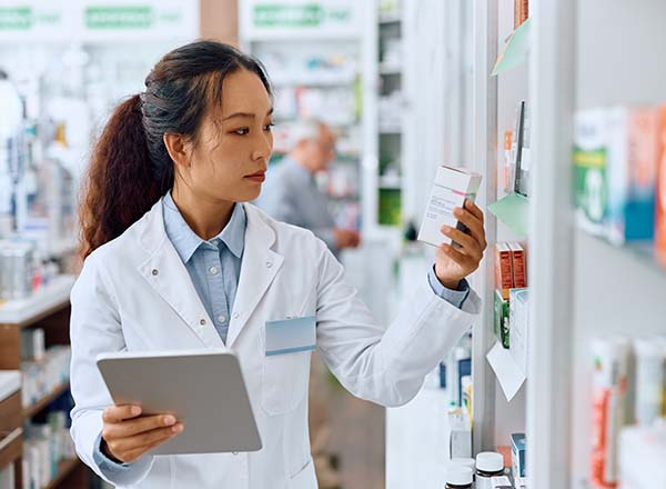 A female pharmacist looking at a box of medicine.