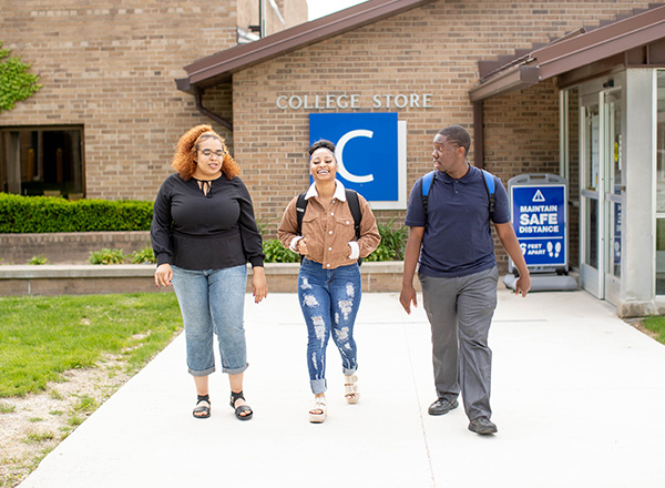 Three HFC students walking out and away from the College Store.