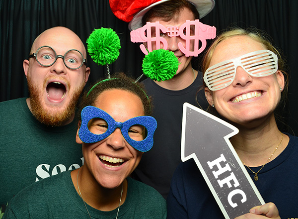 Four students wearing props and fun glasses at a photo booth. 