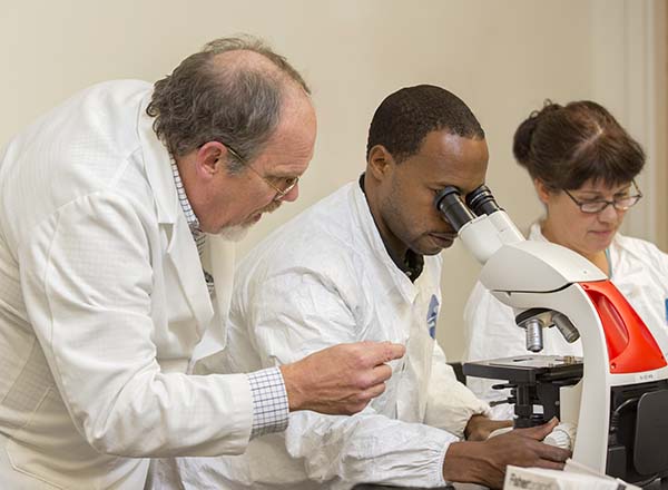 A teacher helping a student with a microscope.