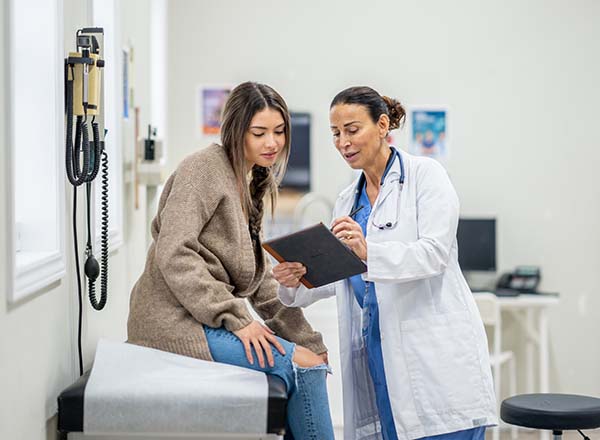 A female doctor showing a female patient information on a tablet.