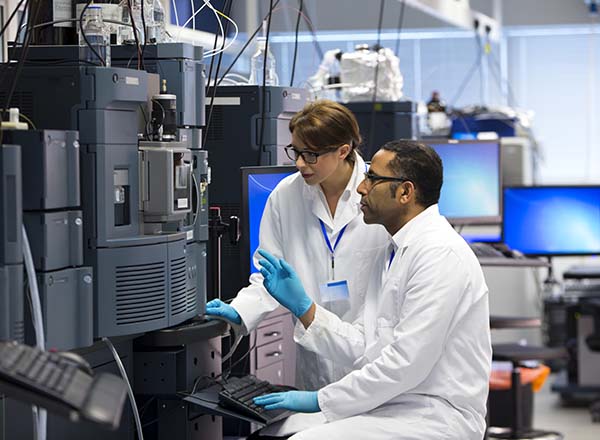 A man and woman sitting at a computer in a lab.