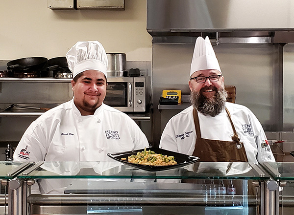 Culinary Wellness chefs smiling behind the counter presenting food.