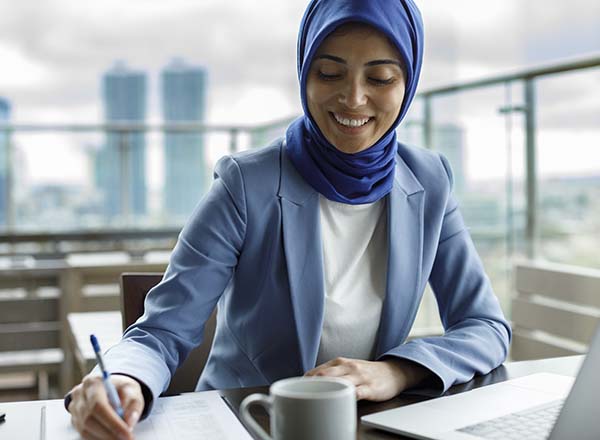 A woman writing while sitting at a table.