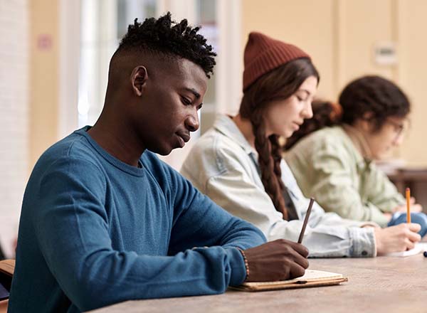 A male student writing at a desk.