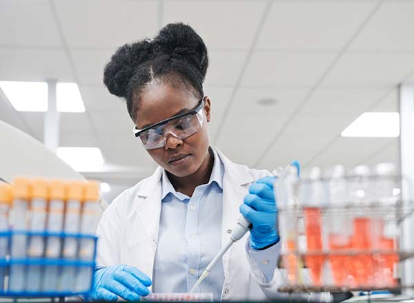 A woman wearing goggles and gloves in a lab.