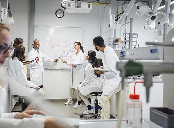 A group of people sitting in a lab around a whiteboard.