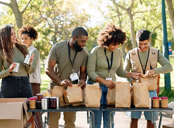 A group of people packing food items outdoors.