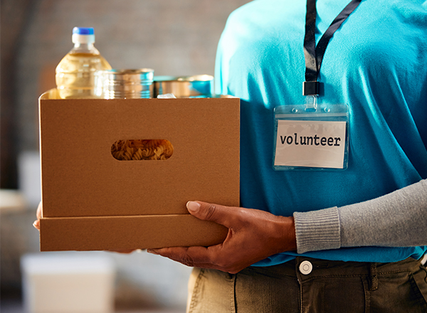 Close up of a woman holding a cardboard box with groceries.