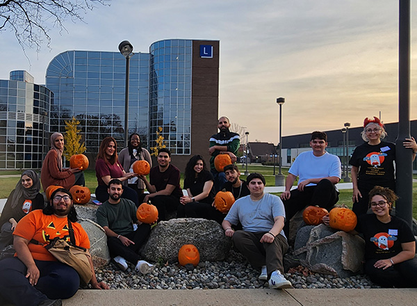 International students outside HFC campus at night with their carved pumpkins.