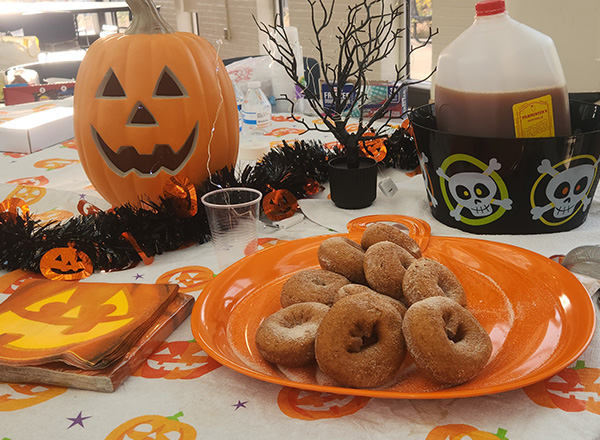 Display of cider and spiced donuts with a jack-o-lantern.