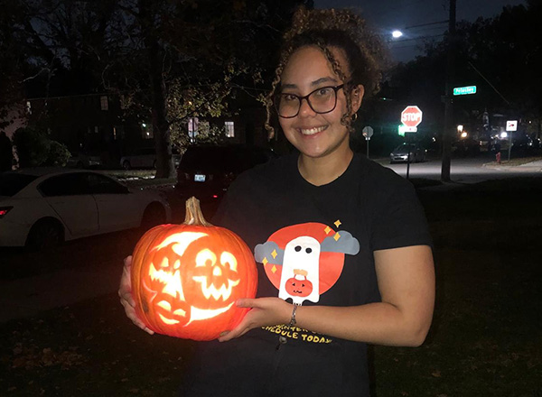 International student with their carved pumpkin lit up.